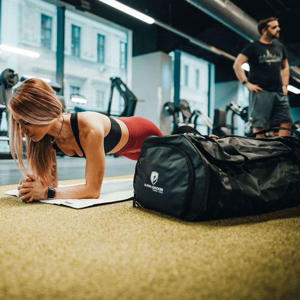 Reisetasche, Sporttasche & Duffel Bag auf dem Boden im Fitnessstudio, ideal für Abenteuer, mit wasserabweisendem Material und vielseitigen Trageoptionen.